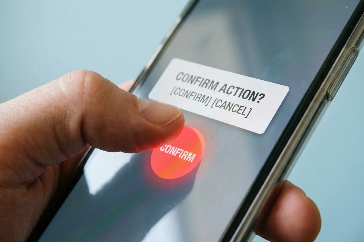 Close-up of hands tapping a red confirm button on a smartphone screen